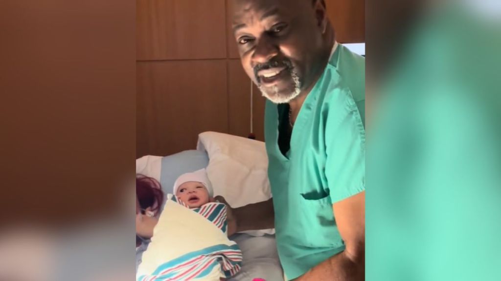 A doctor holding a newborn baby in his arms.