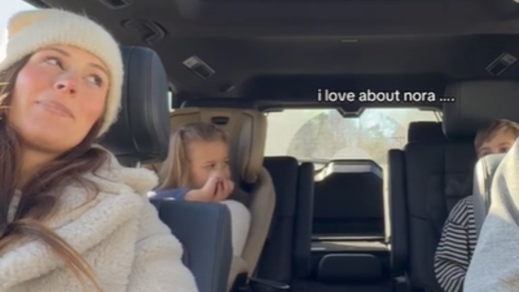 View from the front seat of a vehicle. A woman smirks as she looks back and out of the corner of her eyes at her two kids in the back. Text on the image reads: I love about Nora...