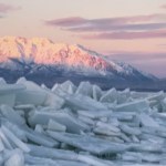 A large pile of ice shoves rests at Utah Lake. In the distance there's a massive snow-covered mountain