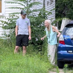 an elderly woman looking at her yard in amazement while standing next to a young man