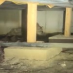 View of the crawl space under a home. In the distance a creature can be seen starting to crawl being a beam. The creature is hidden and a bit blurry