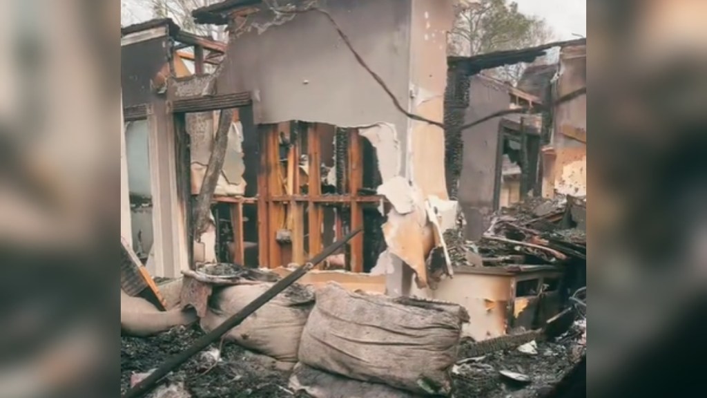 Interior view of a house burned down from a fire. A wall still stands but nearly everything is burnt and falling apart