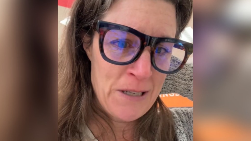 Close up of a woman talking to the camera. There are tears in her eyes