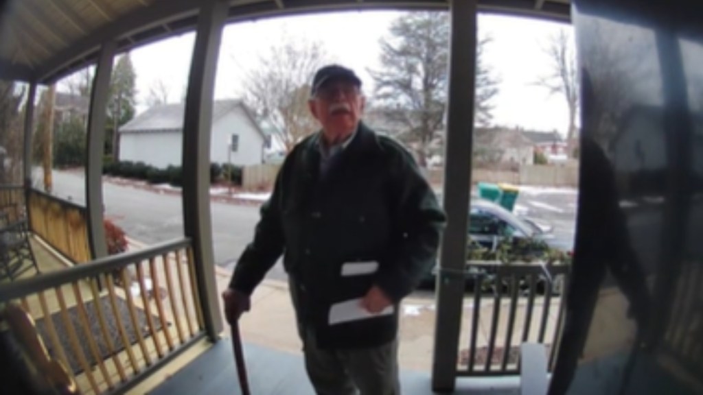 An elderly man stands at someone's front door, letter in hand, as he eagerly waits