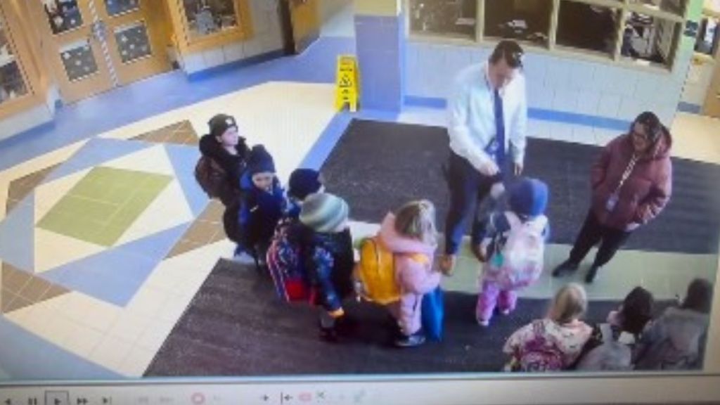 Image shows a school principal interacting with a small group of students.