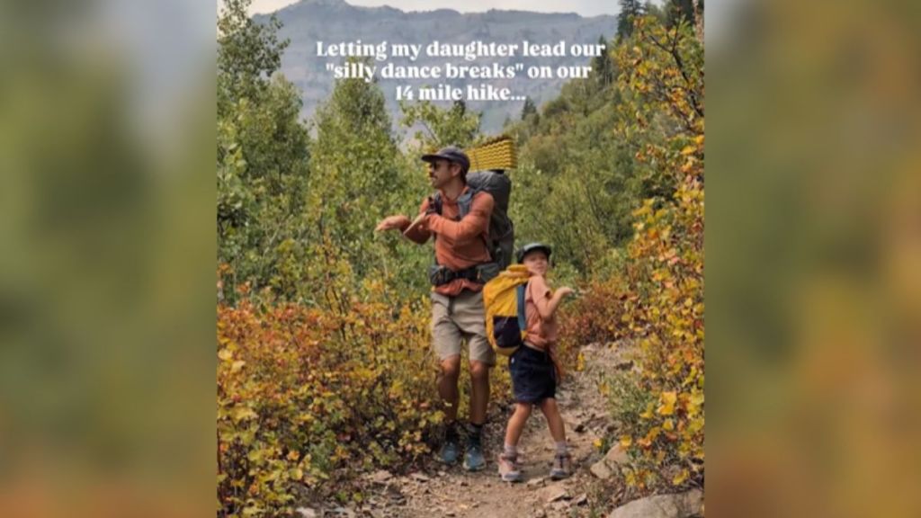 A father and daughter dancing on a nature trail.