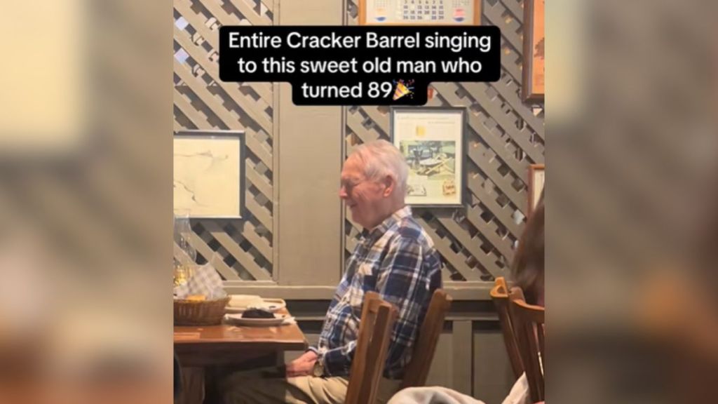 An elderly man sitting at a table in a restaurant.