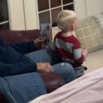 A grandpa and a toddler watching television together.