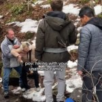 Two men stand near each other, looking on at Mom and Dad. Dad helps Mom who is struggling to walk over a small creek. She looks distressed. Text on the image reads: POV: Hiking With Your Unathletic Family