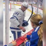 A hockey player handing a puck to the audience.