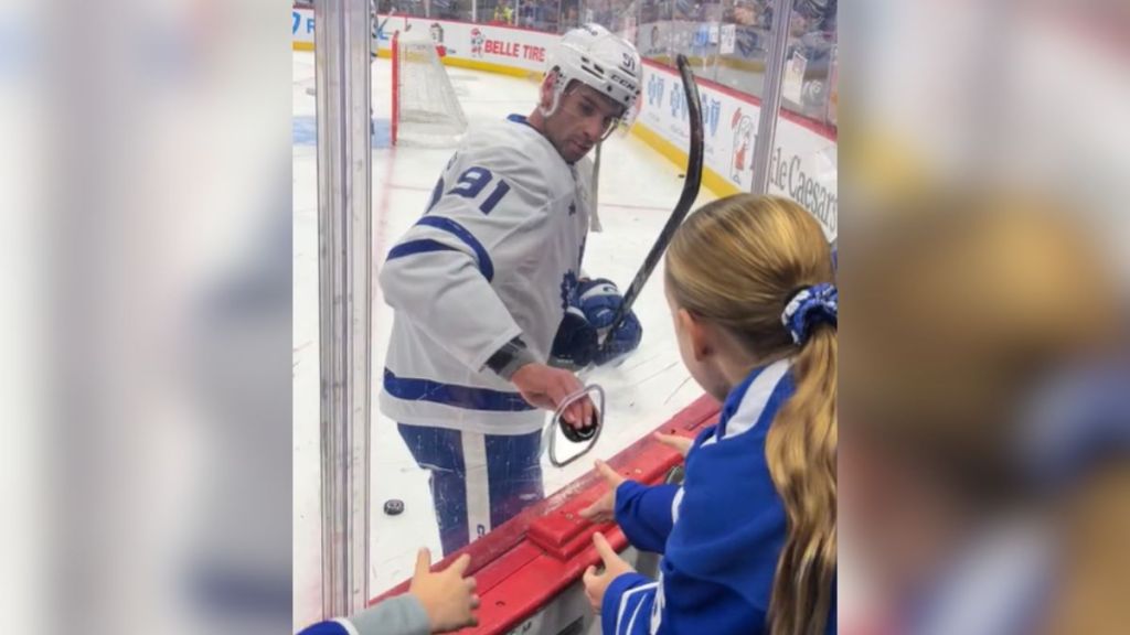 A hockey player handing a puck to the audience.