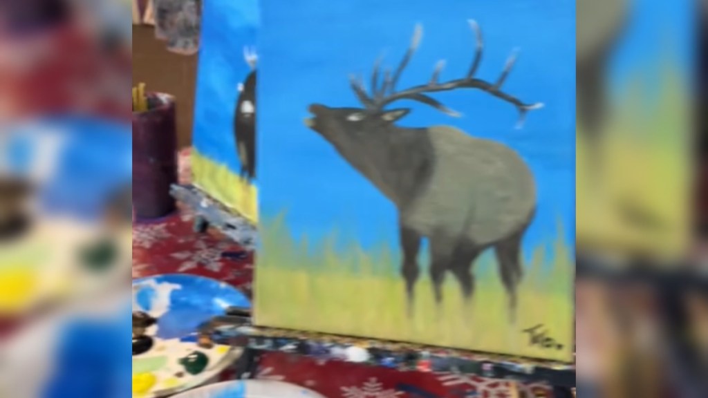 Close up of two paintings. One shows a fairly well painted moose. Peaking out from behind this painting is another one of a moose, this one much sillier looking. But it's not in full view