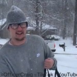 Close up of a man walking in a snowstorm. He's holding a pizza delivery box