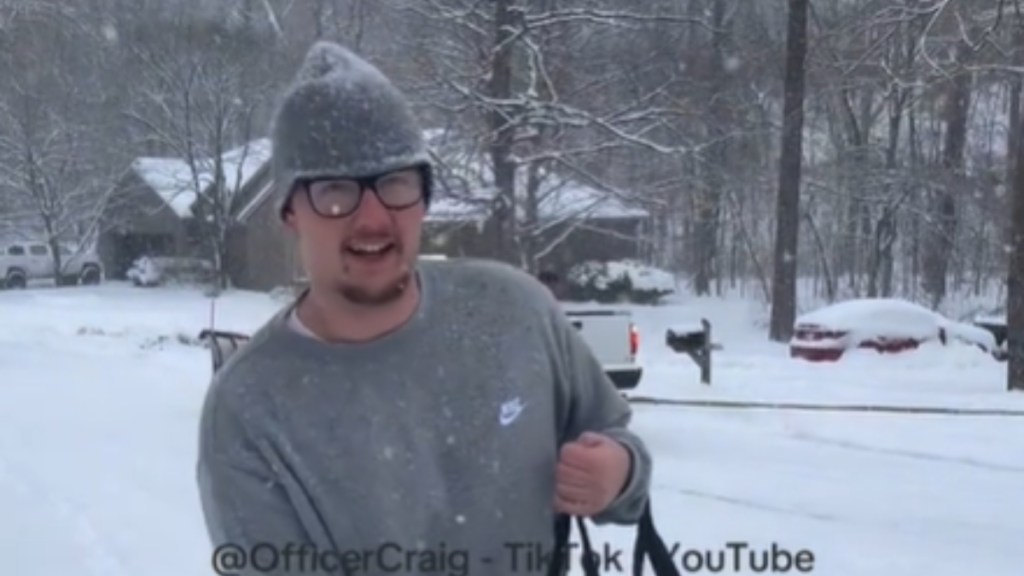 Close up of a man walking in a snowstorm. He's holding a pizza delivery box