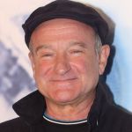 Robin Williams wearing a hat and smiling.