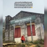 A little boy waving outside a school in Vietnam.