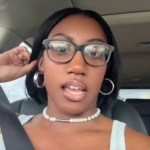 A woman talks into the camera as she sits in her car