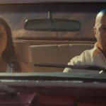 Michelle Rodriguez and Vin Diesel sit in a car. She's in the passenger seat and he's driving. They both look concerned and focused