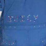 Image shows the word "JUICY" bedazzled on the back of a man's coveralls.