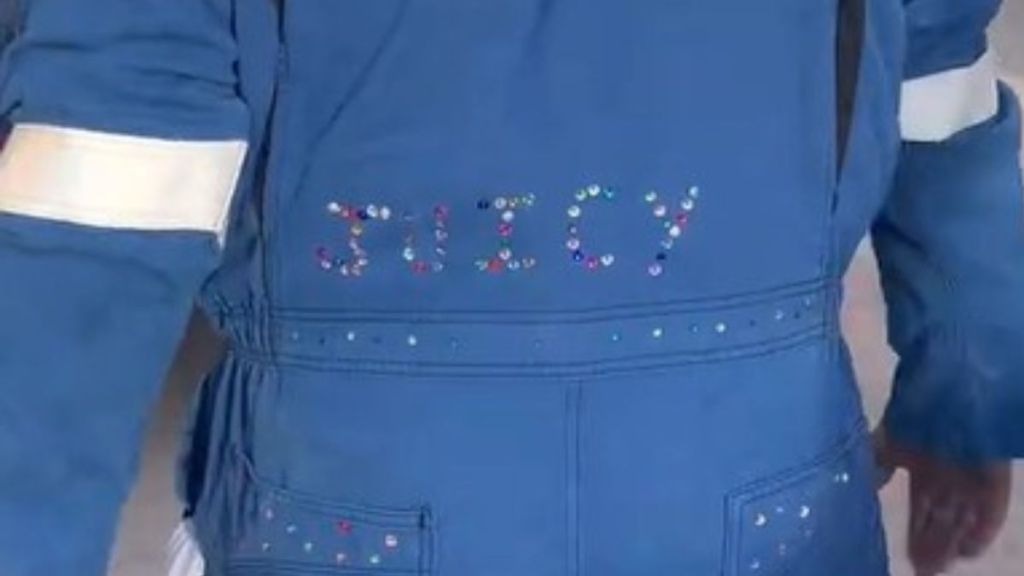 Image shows the word "JUICY" bedazzled on the back of a man's coveralls.