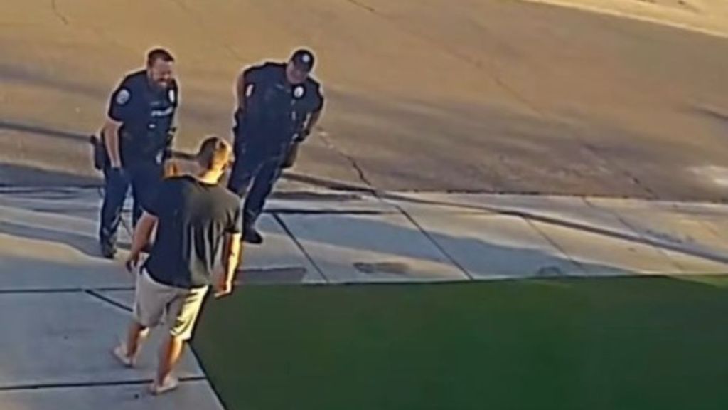 Image shows two police officers questioning a dad about the way his lawn looks.