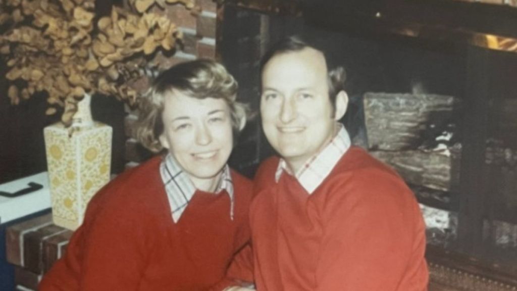 Image shows a picture of Jim and Kay in front of a fireplace from the 1970s.