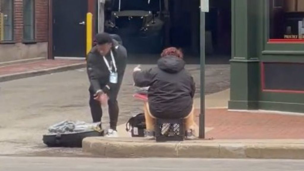 Image show NFL QB Malik Willis offering clothes to a homeless woman.