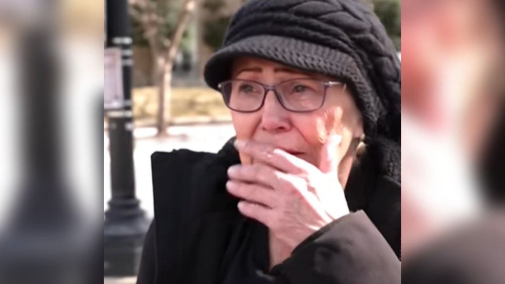 Close up of Pamela Hemphill standing outside, looking emotional. She's covering her mouth with her hand and looks on the verge of tears