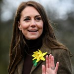 Kate Middleton walks outside. She smiles and waves as she looks back.