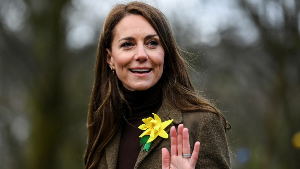 Kate Middleton walks outside. She smiles and waves as she looks back.