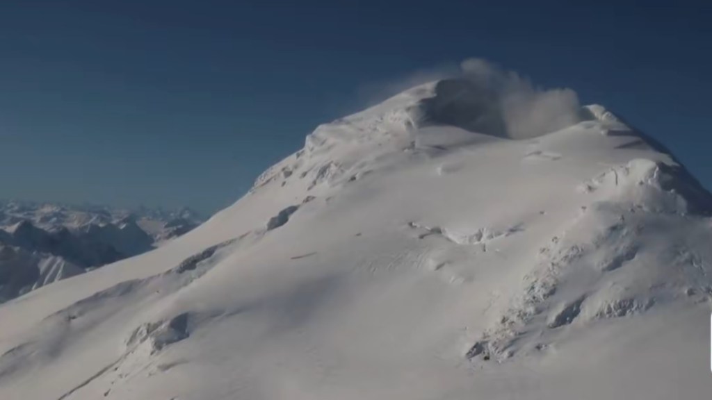 Aerial view of a snow-covered Mount Spurr. Steam is starting to emit from the volcano